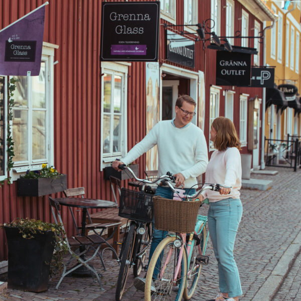 Man och kvinna med cyklar utanför Grenna Glass på Brahegatan i Gränna