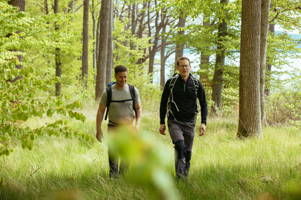 Två män vandrar på John Bauerleden mellan Gränna och Huskvarna, solen skiner