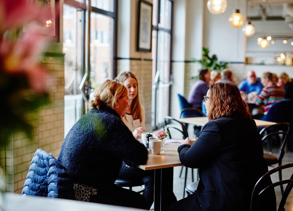 Personer som sitter vid ett runt bord på en restautang.