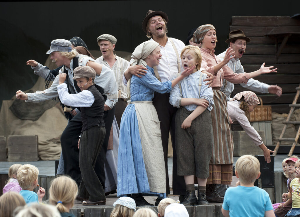 Eine Gruppe Menschen in historischer Kleidung spielt in einem Theaterstück.