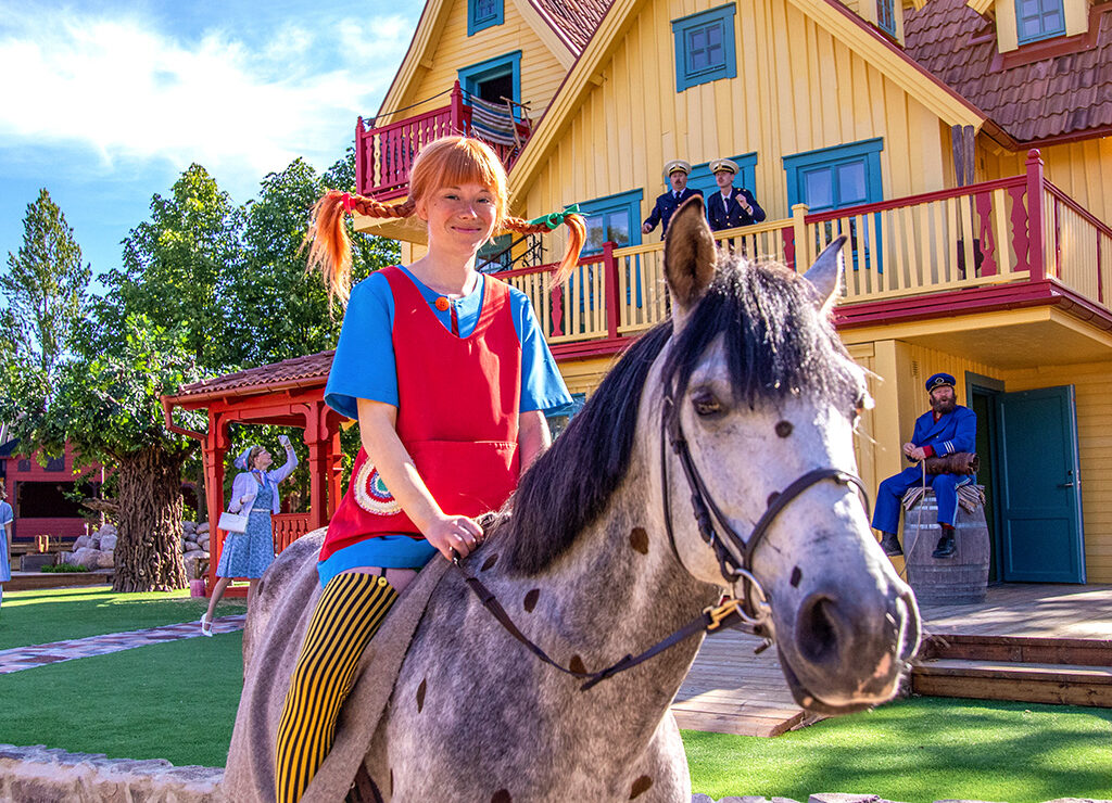 Pippi Langstrump auf ihrem Pferd vor der Villa Kunterbunt.